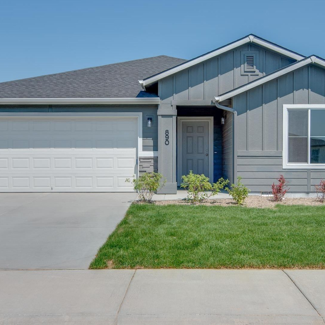 Front of gray house with white garage door and green grass